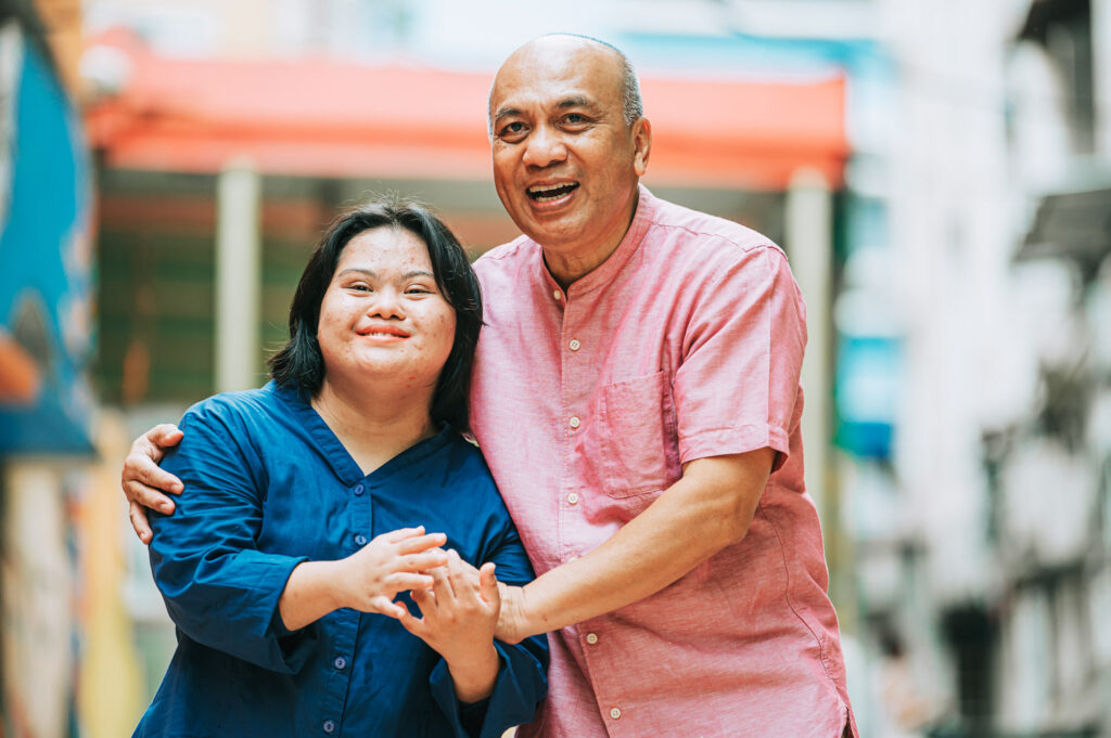 Happy asian woman with autism and Down syndrome holding her father's hands in a city street.