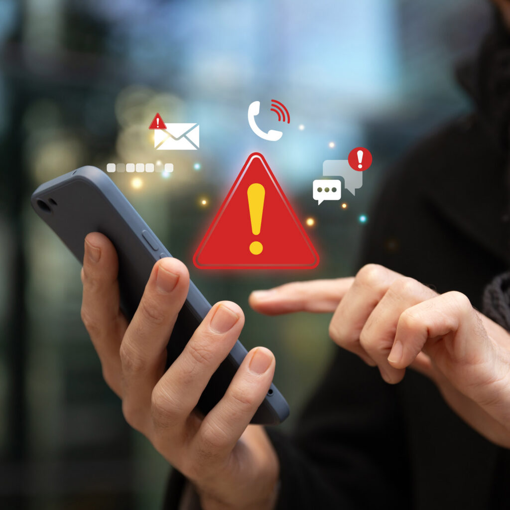 Person using smartphone with red alert and warning icons, representing emergency notifications.