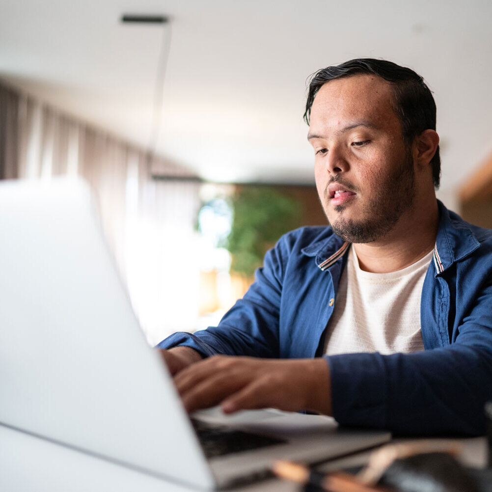 Young man with Down syndrome using the laptop at home.