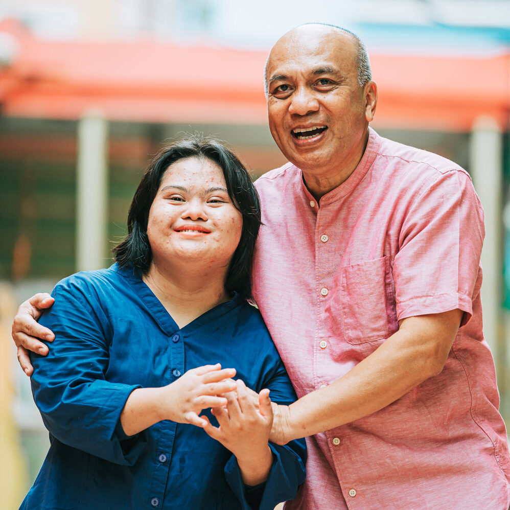 Happy asian woman with autism and Down syndrome holding her father's hands in a city street.